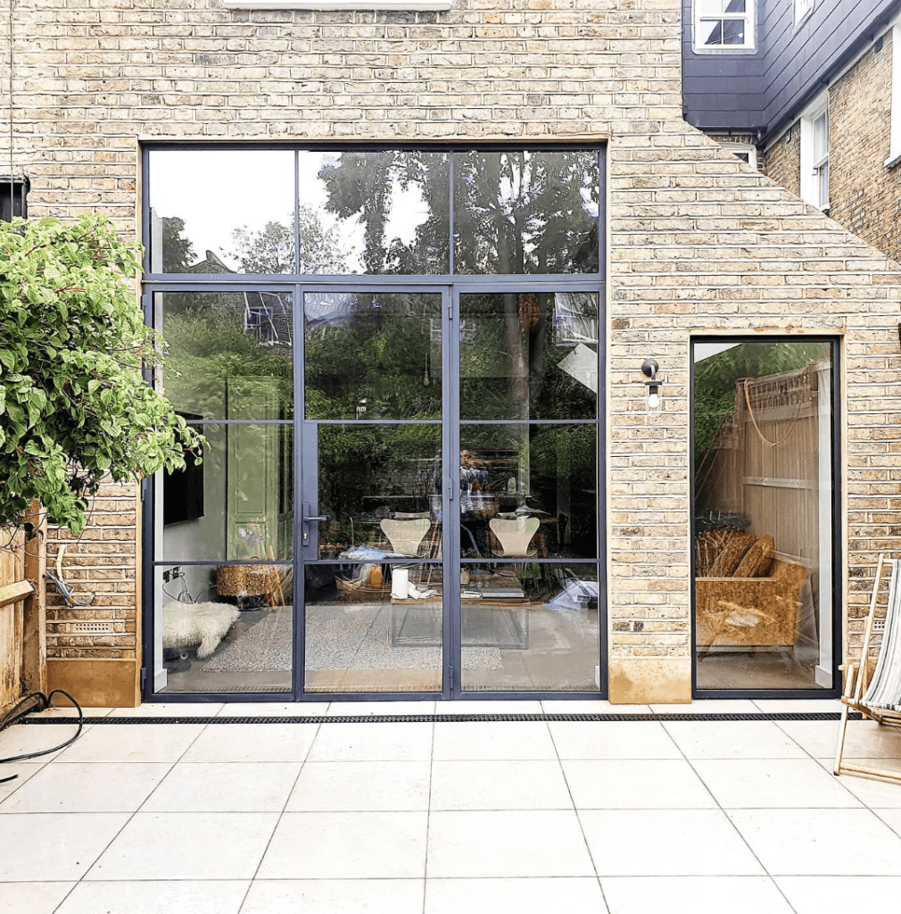 External black steel French doors opening onto the patio of a brick house
